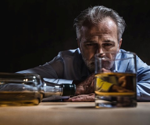 Man looking at a glass of alcohol